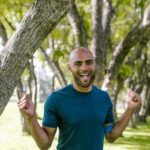 Vibrant scene of a joyful man in a park during daytime, exuding happiness and energy.